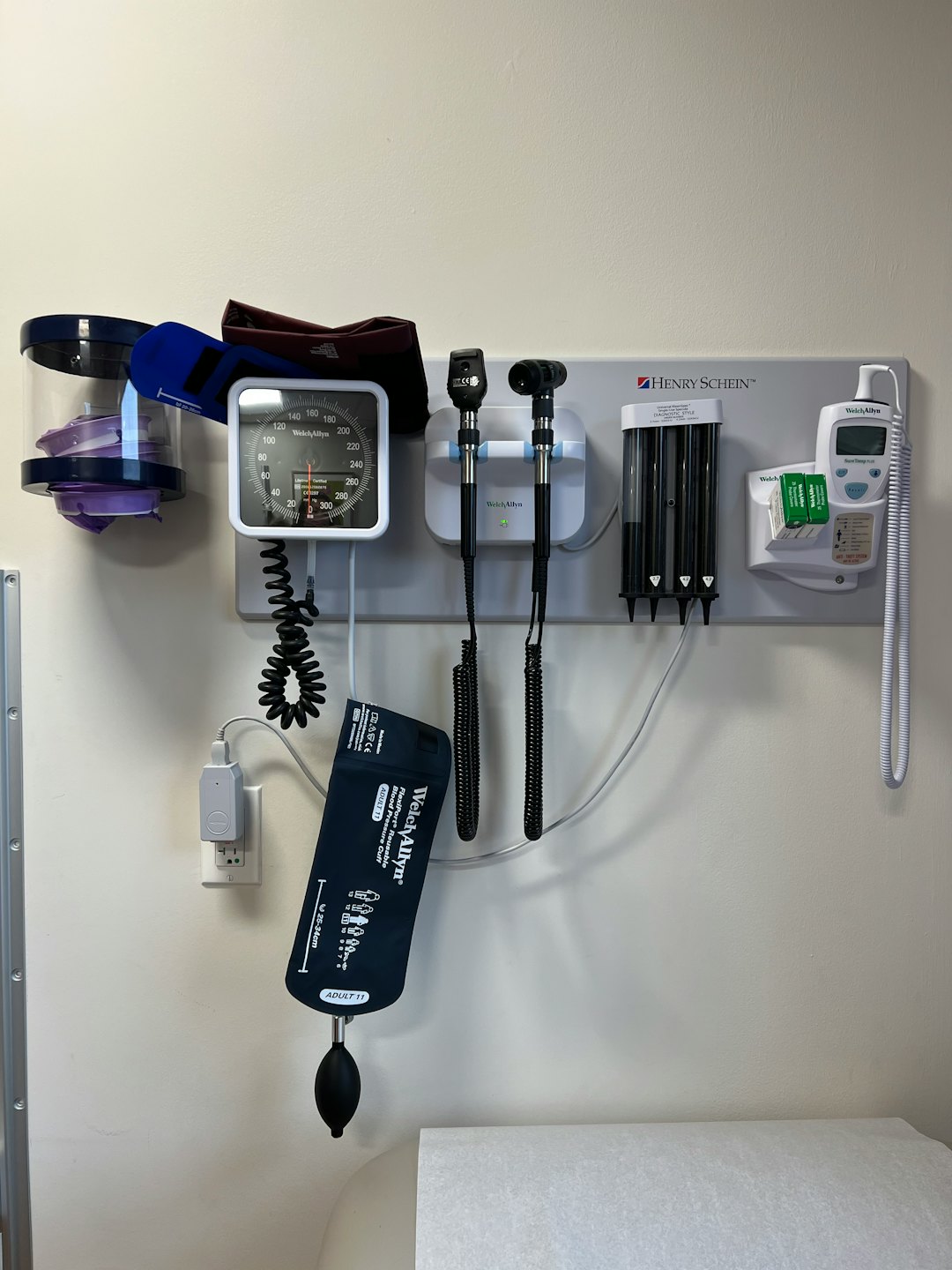 Nástenná lekárska diagnostická stanica s monitorom krvného tlaku a vyšetrovacími nástrojmi.